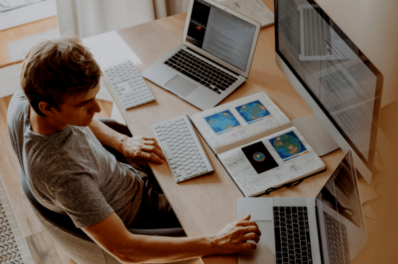Man viewing laptop screen, typing and working on multiple windows