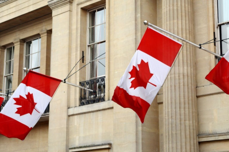 Canadian flags waving on the side of the building