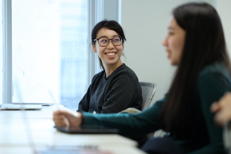Two women smiling while using a laptop