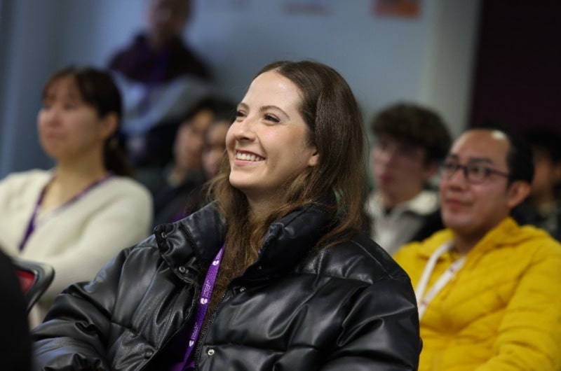 Woman smiling, wearing ID card, posing for photo