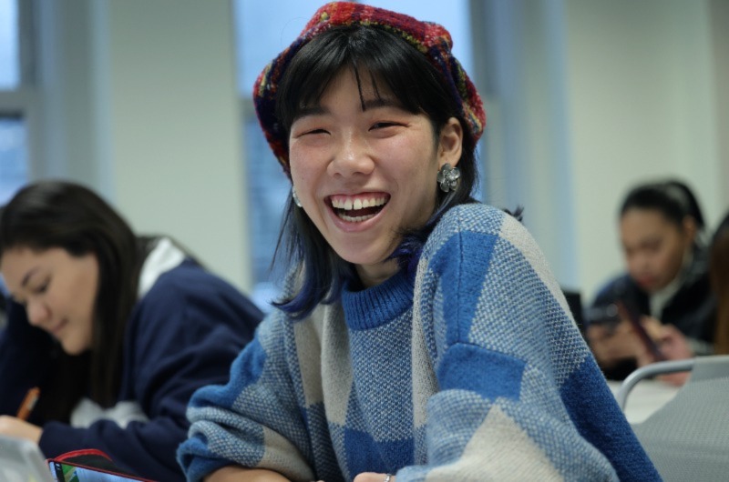 Woman smiling, hands folded, posing for photo