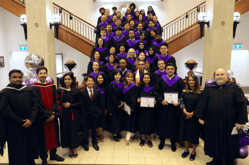 Graduate students dressed in caps and gowns celebrate their graduation
