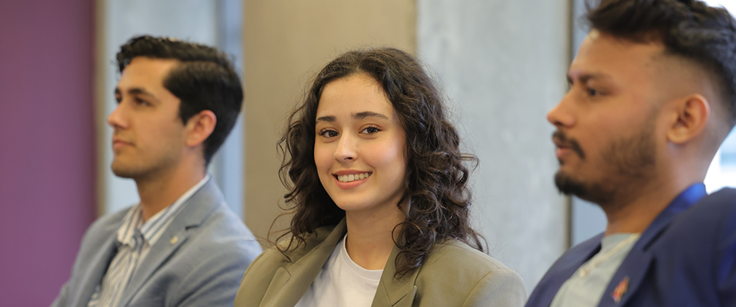 Three people seated, with the person in the center smiling at the camera