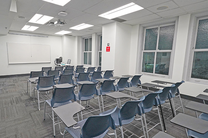 Empty classroom with rows of desks facing a whiteboard